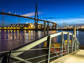 Bridge across the river, at night, with lights and buildings.