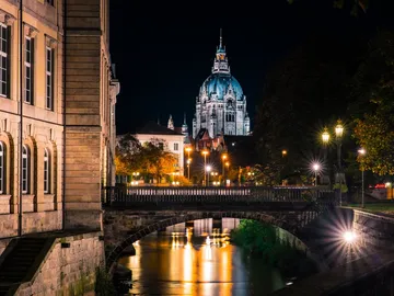A building glows at night, reflected in the water of a canal.