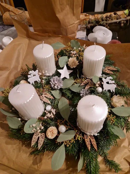 Adventskranz mit weißen Kerzen und Grün.