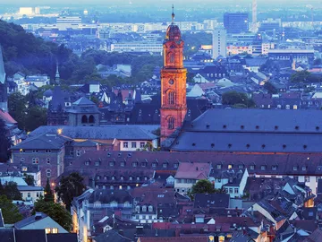 City view with an illuminated church tower at dusk.