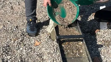 Gold panning over a sluice, gravel background.