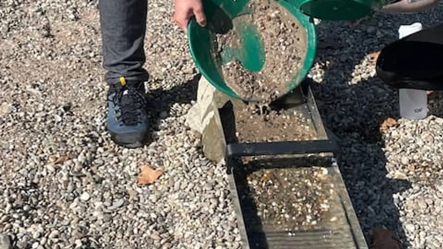 Gold panning over a sluice, gravel background.