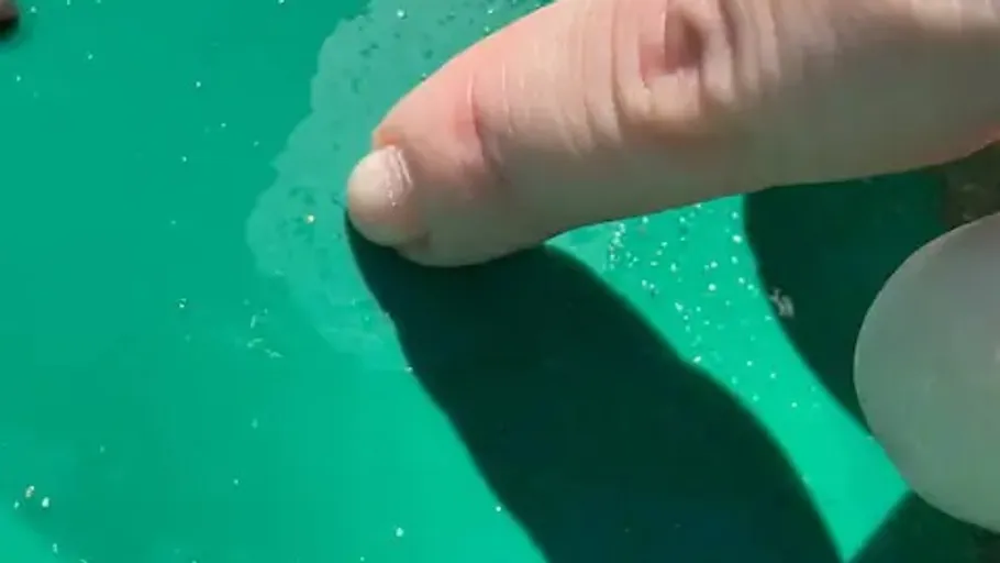 Finger pointing at small gold flakes on pan.