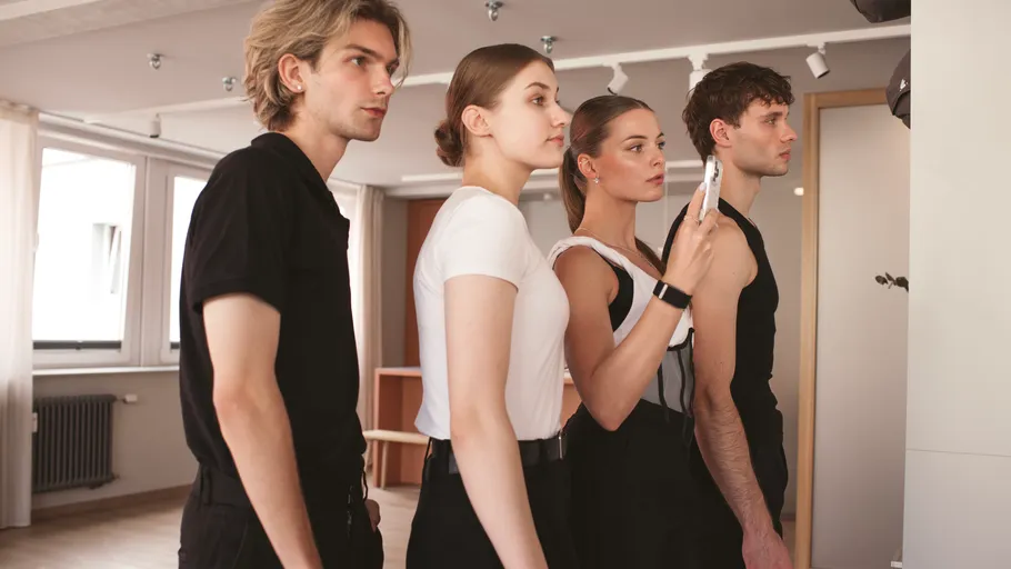Four people stand in a line, indoors.