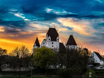 Eine Burg steht majestätisch unter einem bunten Himmel.