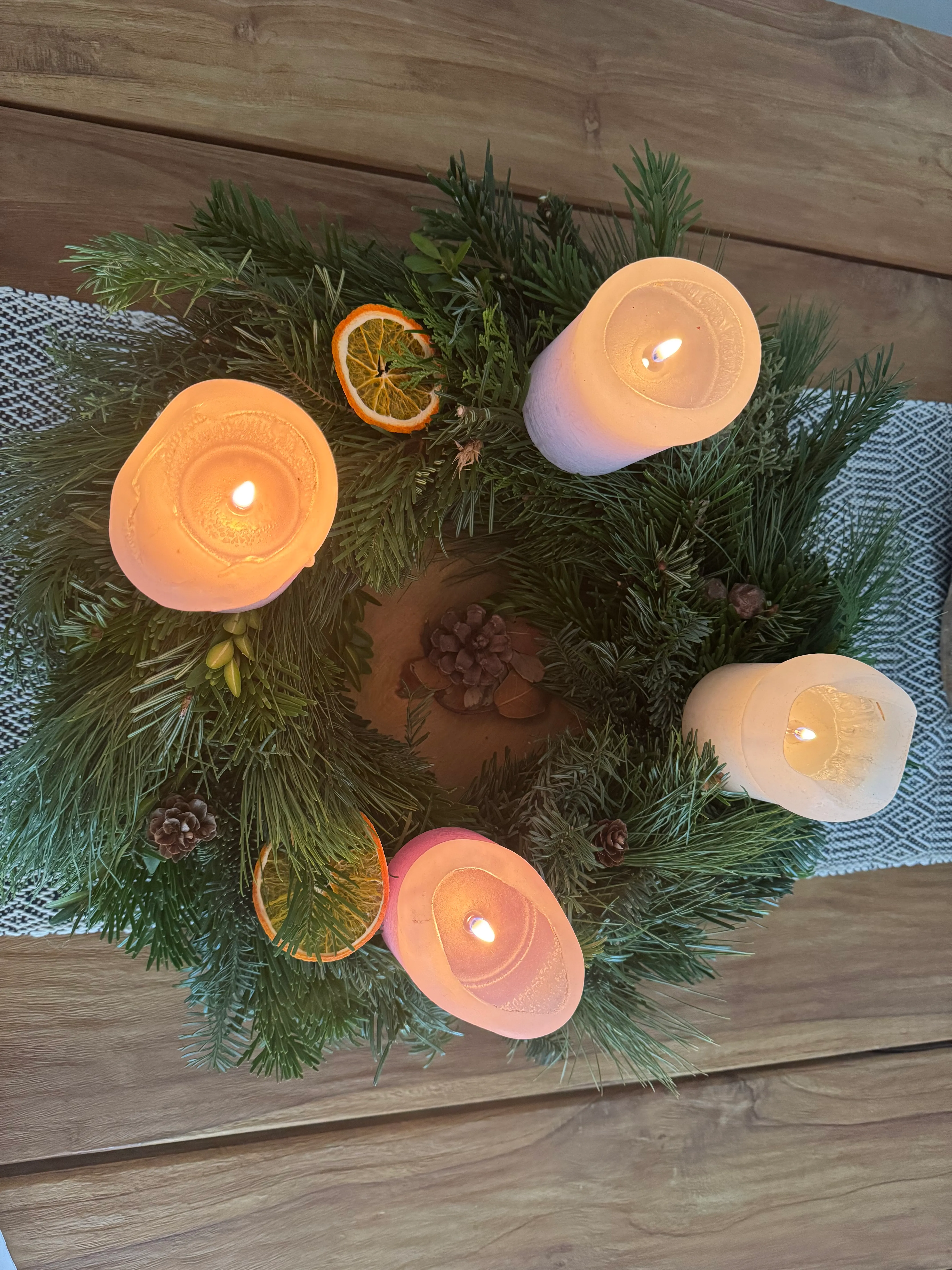 Candles on Christmas wreath on table.