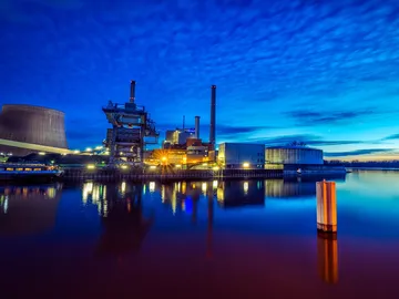 Industrieanlage reflektiert im Wasser, umgeben von Nachtblau.