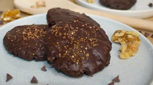 Three chocolate cookies with sprinkles on plate.