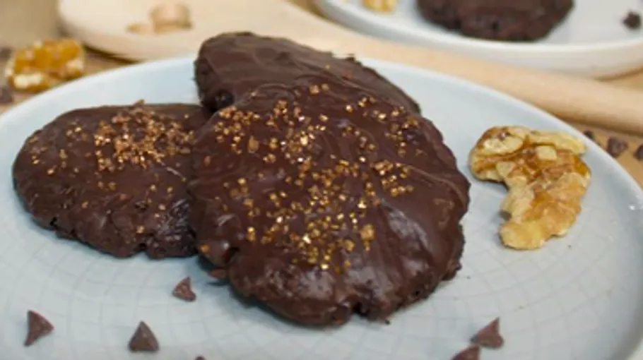 Three chocolate cookies with sprinkles on plate.