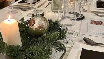 Candle and ornament on festive table setting.