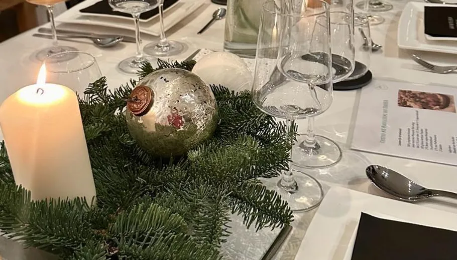 Candle and ornament on festive table setting.