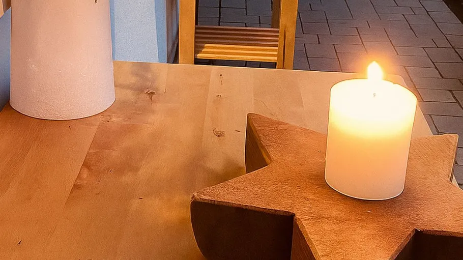 Candle on star base, wooden table.
