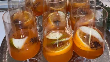 Glasses of spiced punch with fruit slices, indoors.