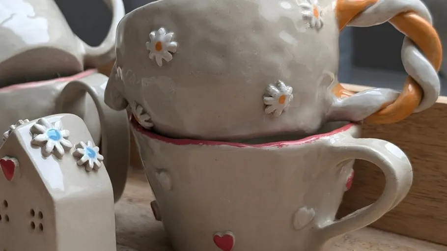 Dekorative Tassen mit Herz- und Blumendesigns.