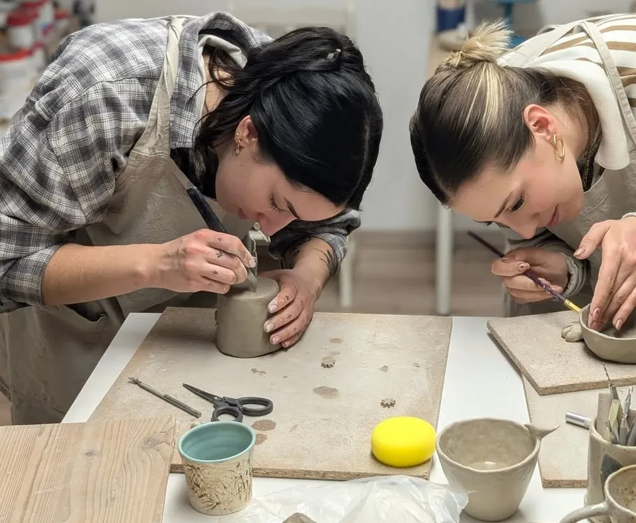 Two women crafting pottery at a table.