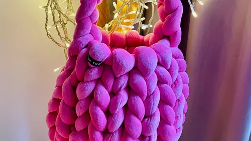 Pink woven bag hanging beside decorative lights.