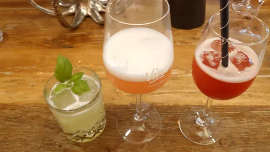 Drei Cocktails auf einem Holztisch.