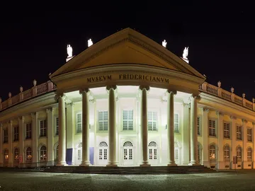 Classic building illuminated, surrounded by night vibes.