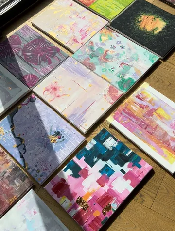 Colorful abstract paintings arranged on wooden floor.