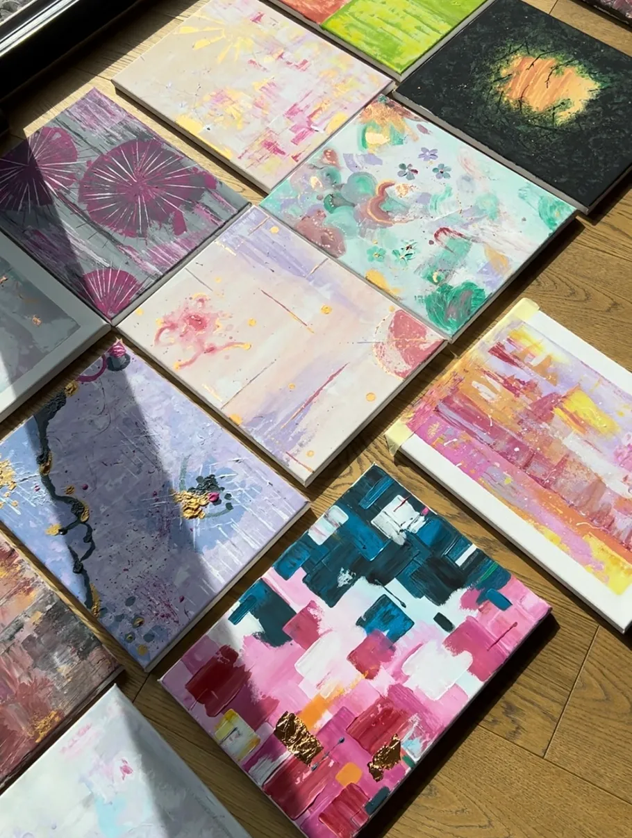 Colorful abstract paintings arranged on wooden floor.