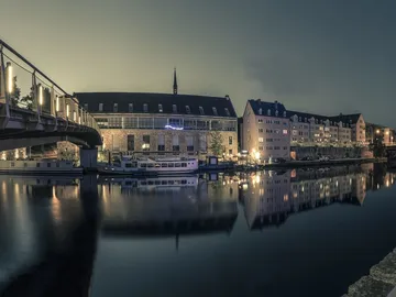 Bridge over calm water surrounded by illuminated buildings.