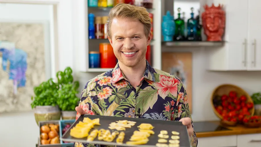 Man holding tray of sliced fruits in kitchen.