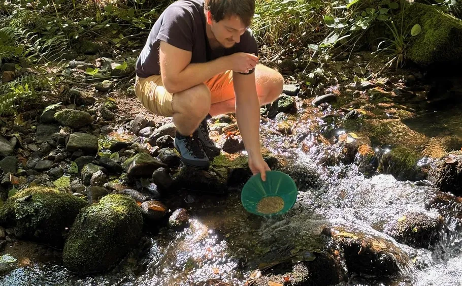 Person panning for gold in a stream.