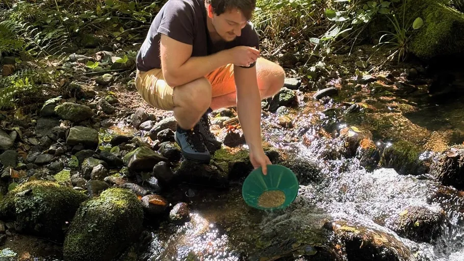 Person panning for gold in a stream.