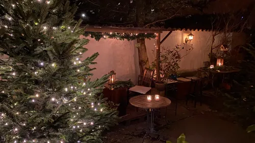Beleuchteter Weihnachtsbaum in gemütlichem Außenbereich.