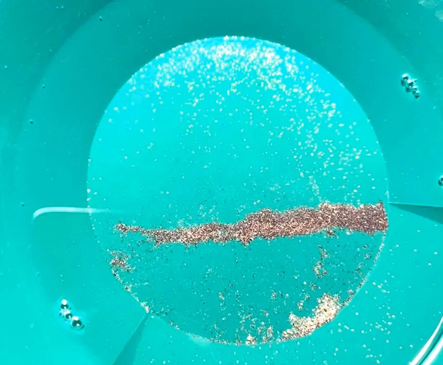 Goldpartikel in blauer Pfanne mit Wasser.