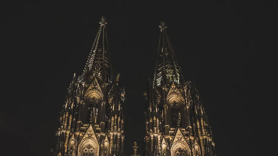 Illuminated cathedral spires at night sky.