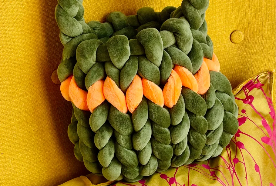 Plush green bag on yellow chair.