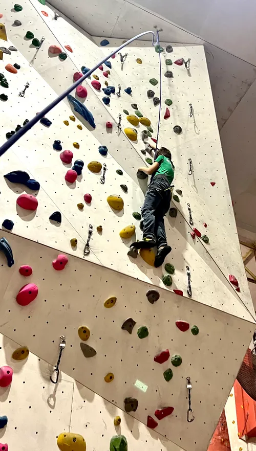 Person klettert an einer Kletterwand.