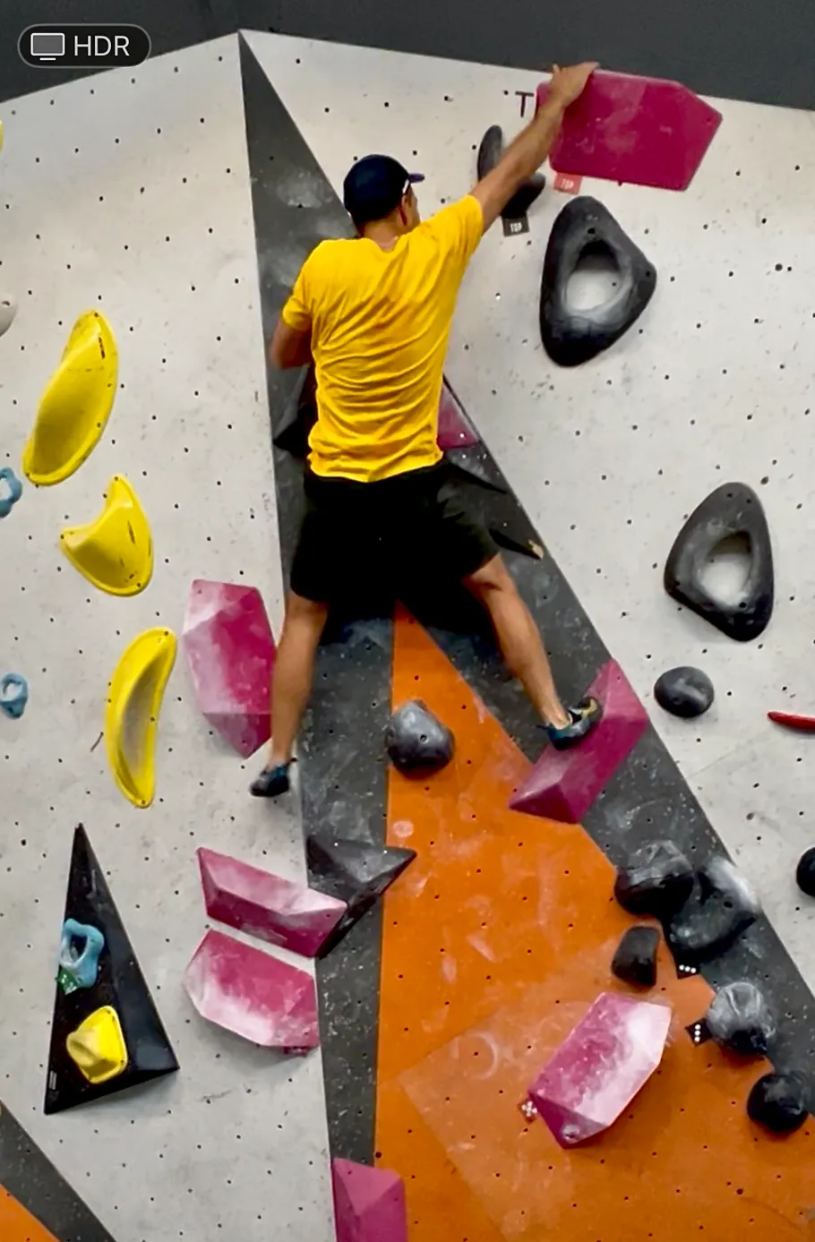 Person climbing indoor rock wall, colorful holds present.