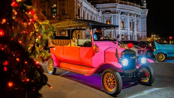 Pink vintage car parked on city street.