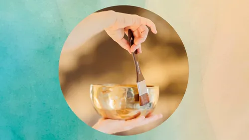 Hand holding brush touching golden bowl.