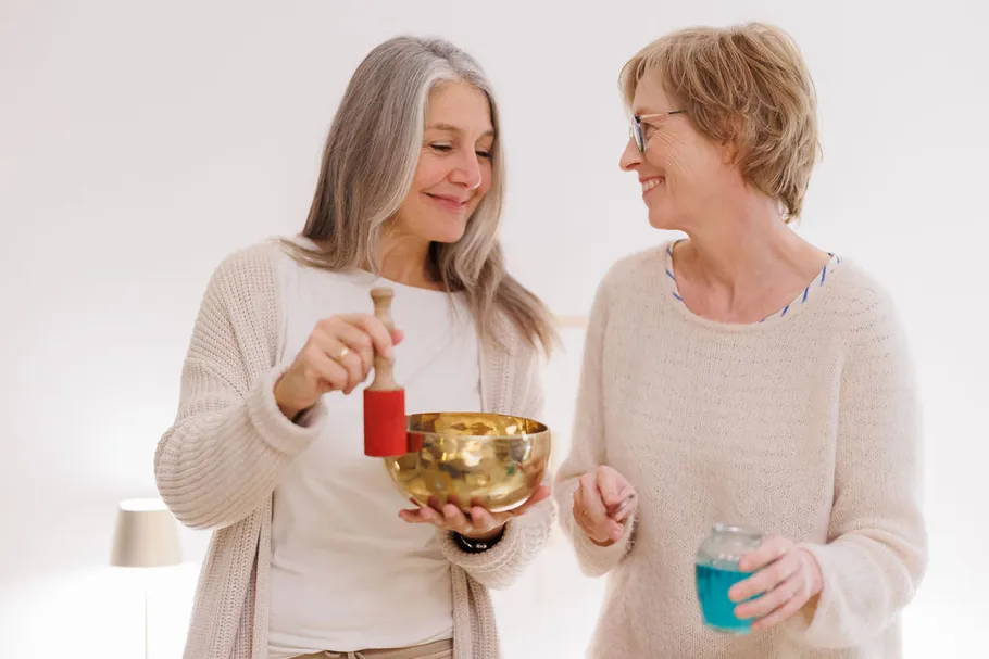 Two women smiling with sound bowl indoors.