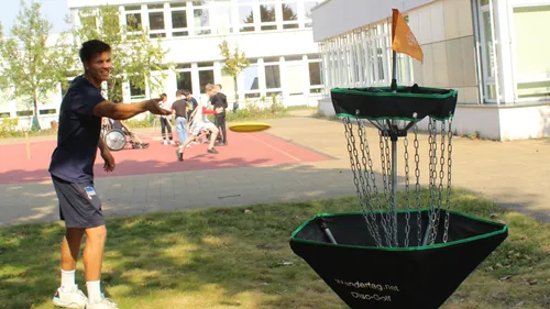 Man playing disc golf at school yard.