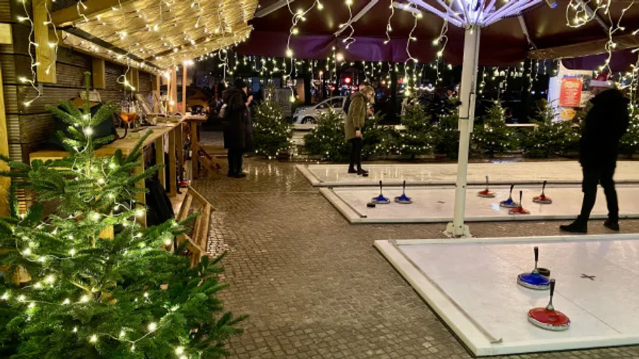 Outdoor-Eisstockspiel, Menschen spielen, festliche Lichter.