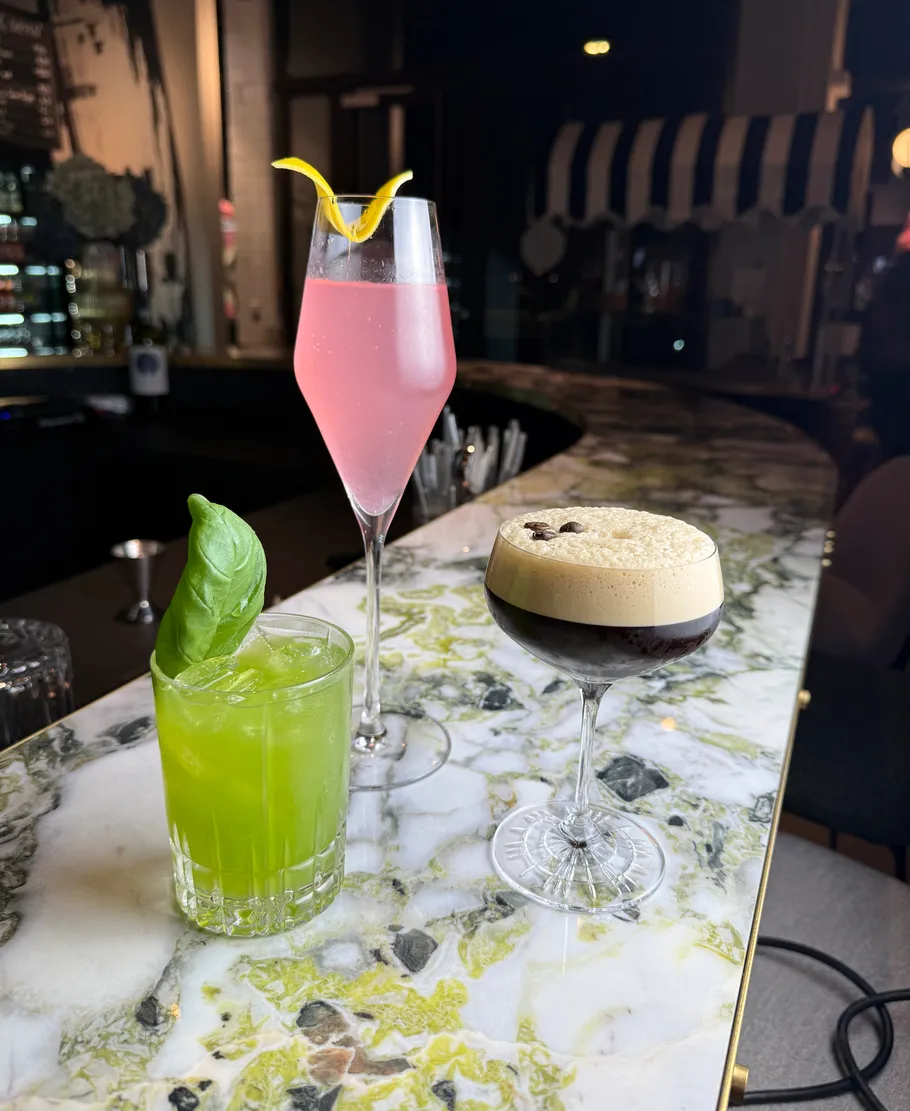 Drei bunte Cocktails auf einer Marmorbar.