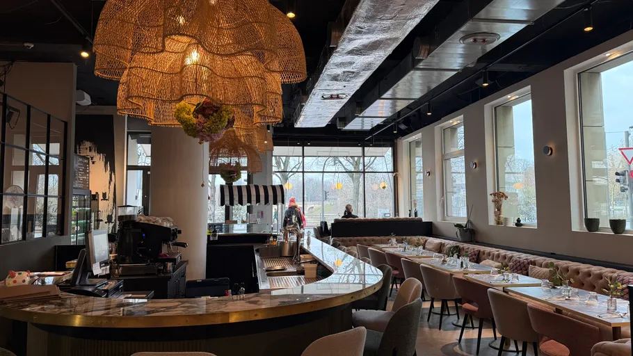 Modern cafe with large windows and seating.