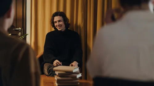 Man sitting, smiling at others in room.