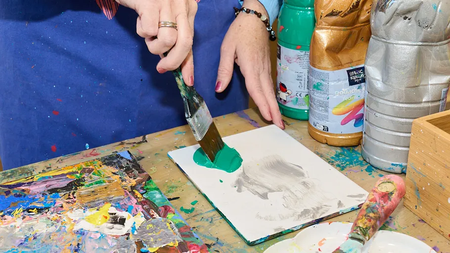 Person painting with green paint on paper.