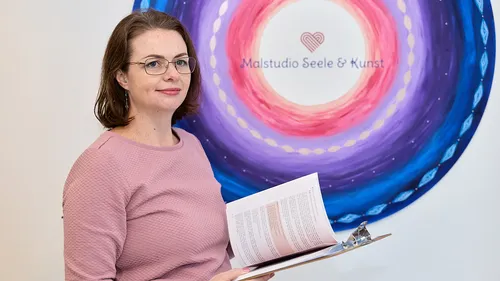 Frau mit Klemmbrett, gemaltes Wandbild im Hintergrund.
