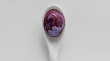 Purple sauce on white ceramic spoon.