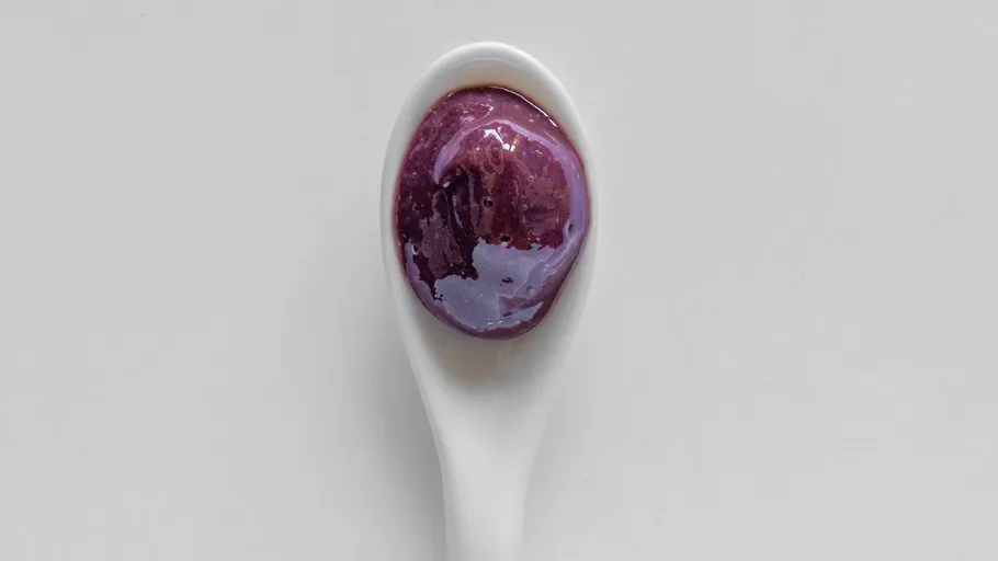 Lila Soße auf weißem Keramiklöffel.