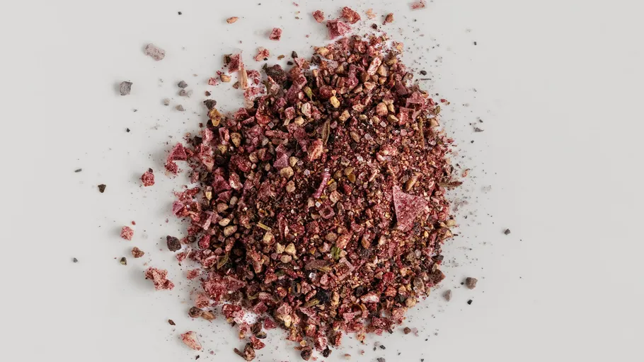 Pile of crushed red spices on white surface.