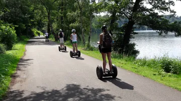 Personen fahren Segways auf Seeuferweg.