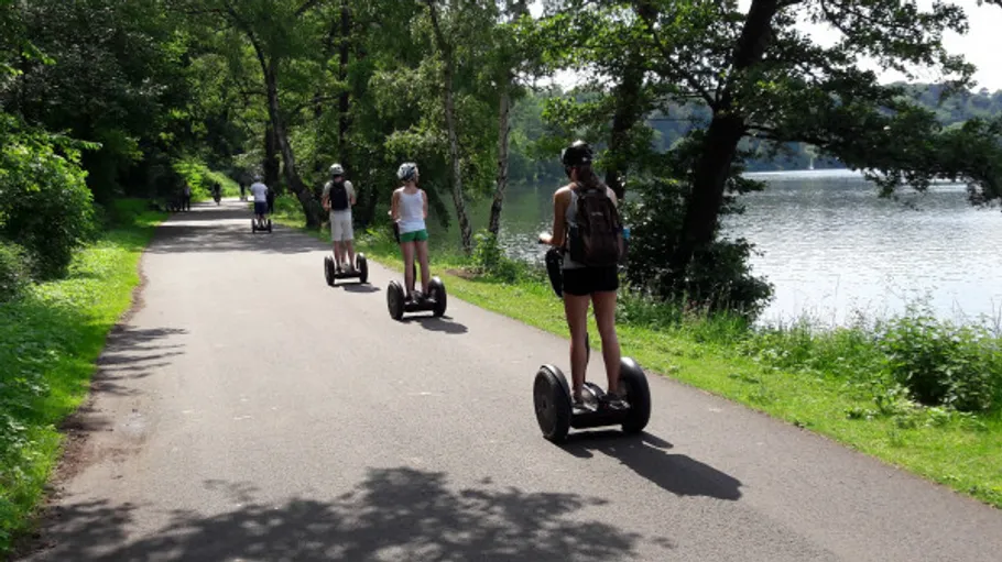 People riding segways on lakeside path.