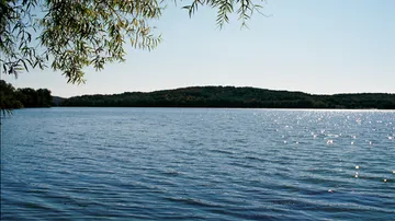Lake with trees and hills in background.